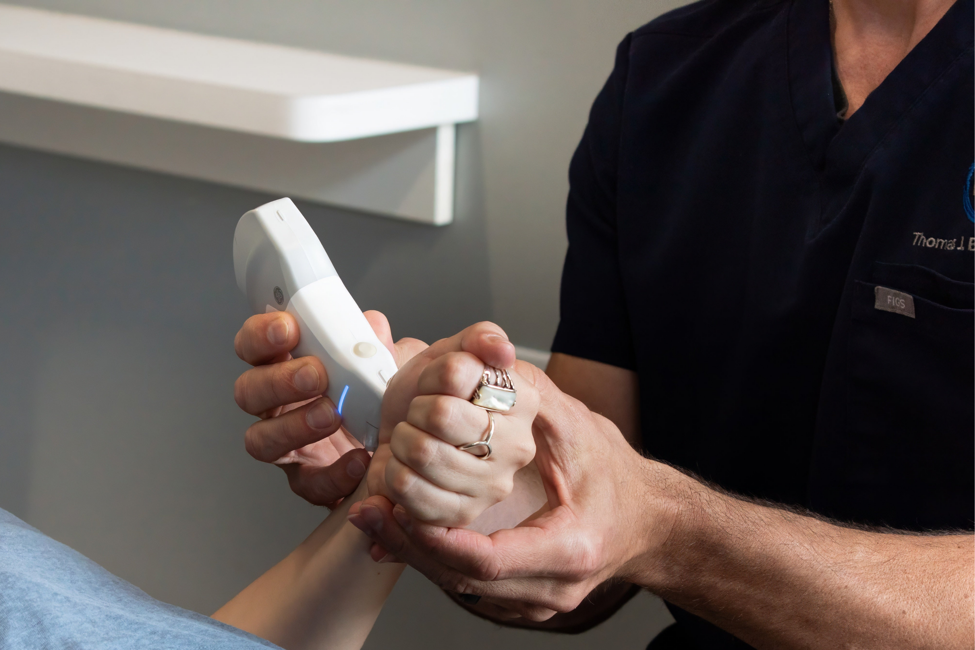 Person holding a digital device on a patient's hand in a clinical setting