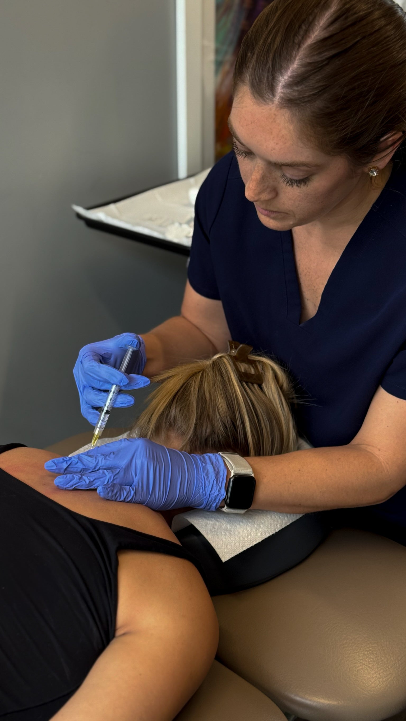 Person receiving an injection from a healthcare professional in a medical setting.