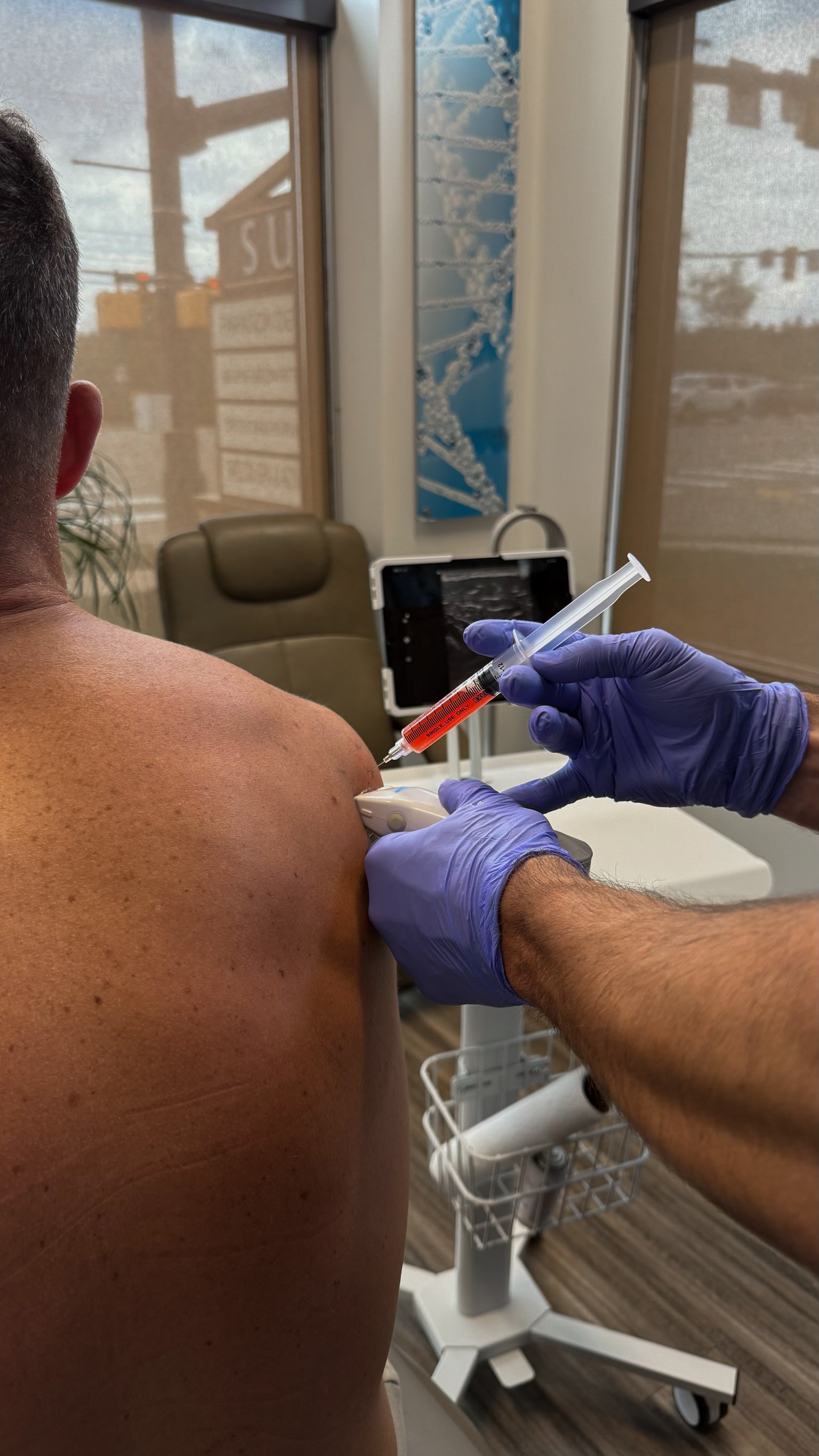 Person receiving an injection from another person wearing gloves in a medical setting.