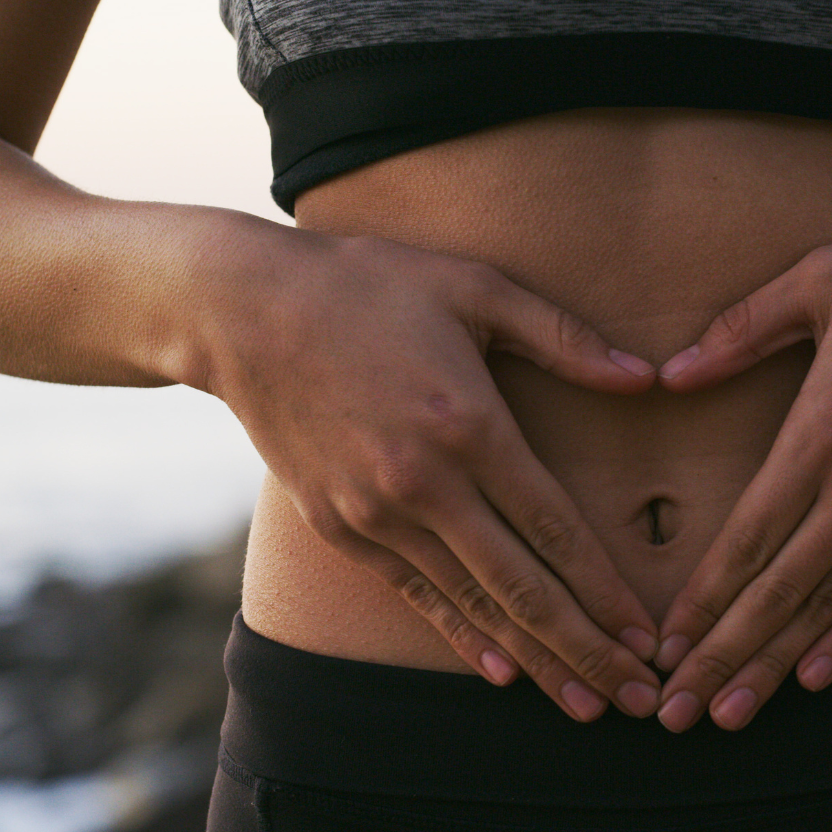 Person forming a heart shape with their hands over their stomach