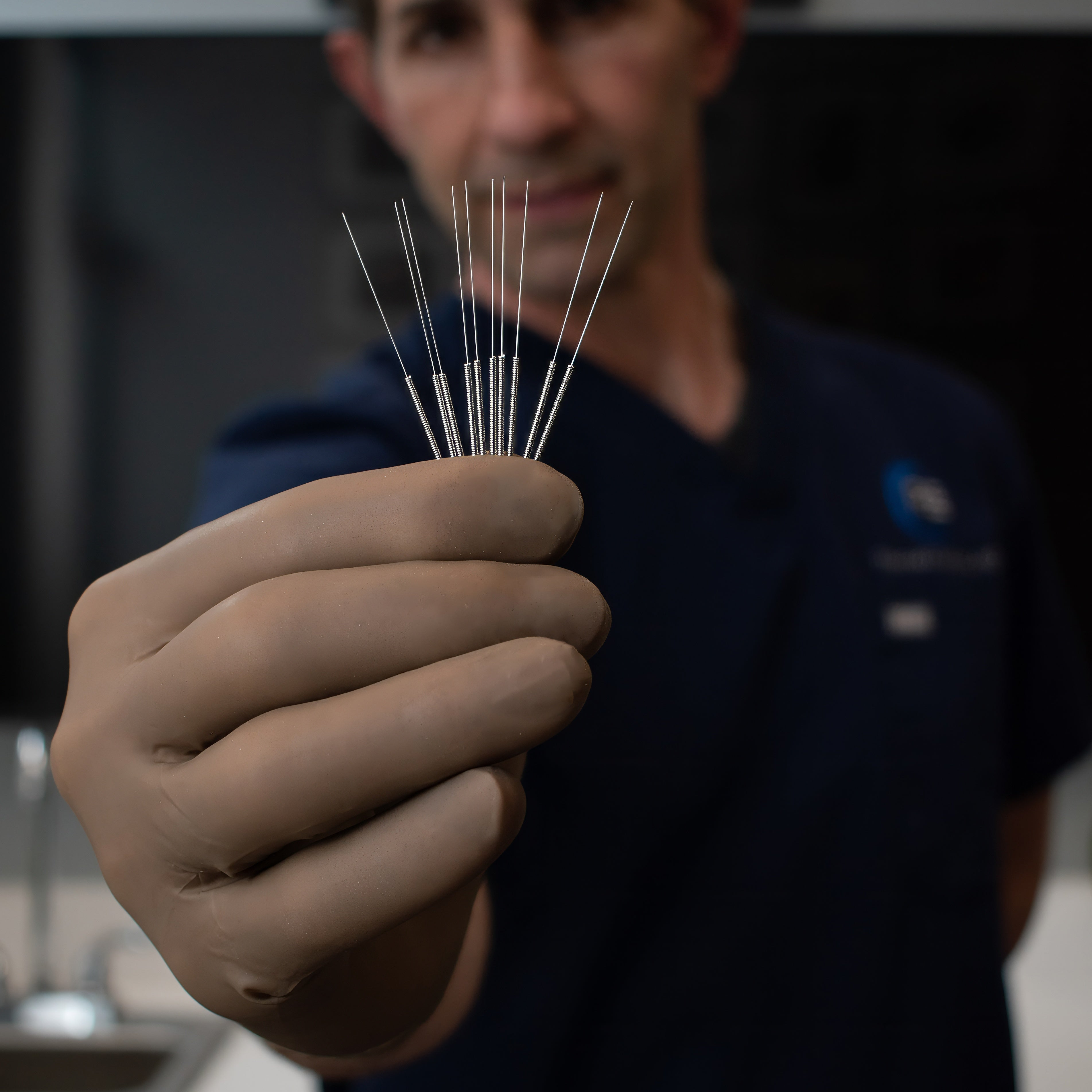 Person holding acupuncture needles with a blurred background