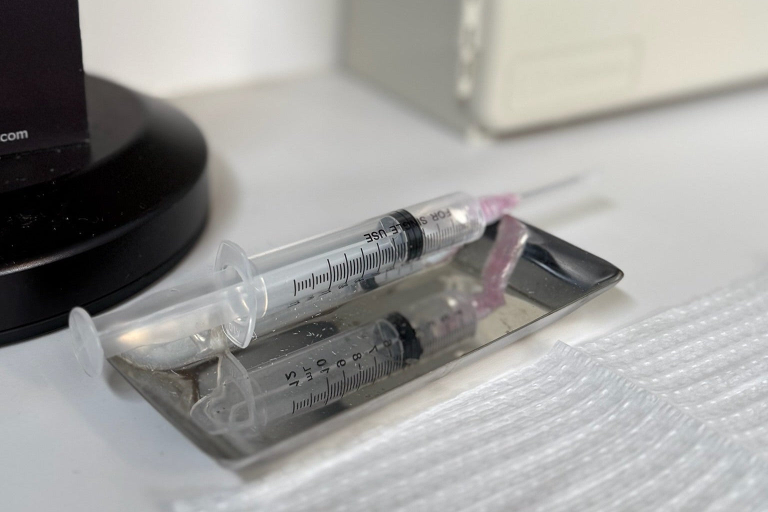 Medical syringe and vial on a white surface with a blurred background