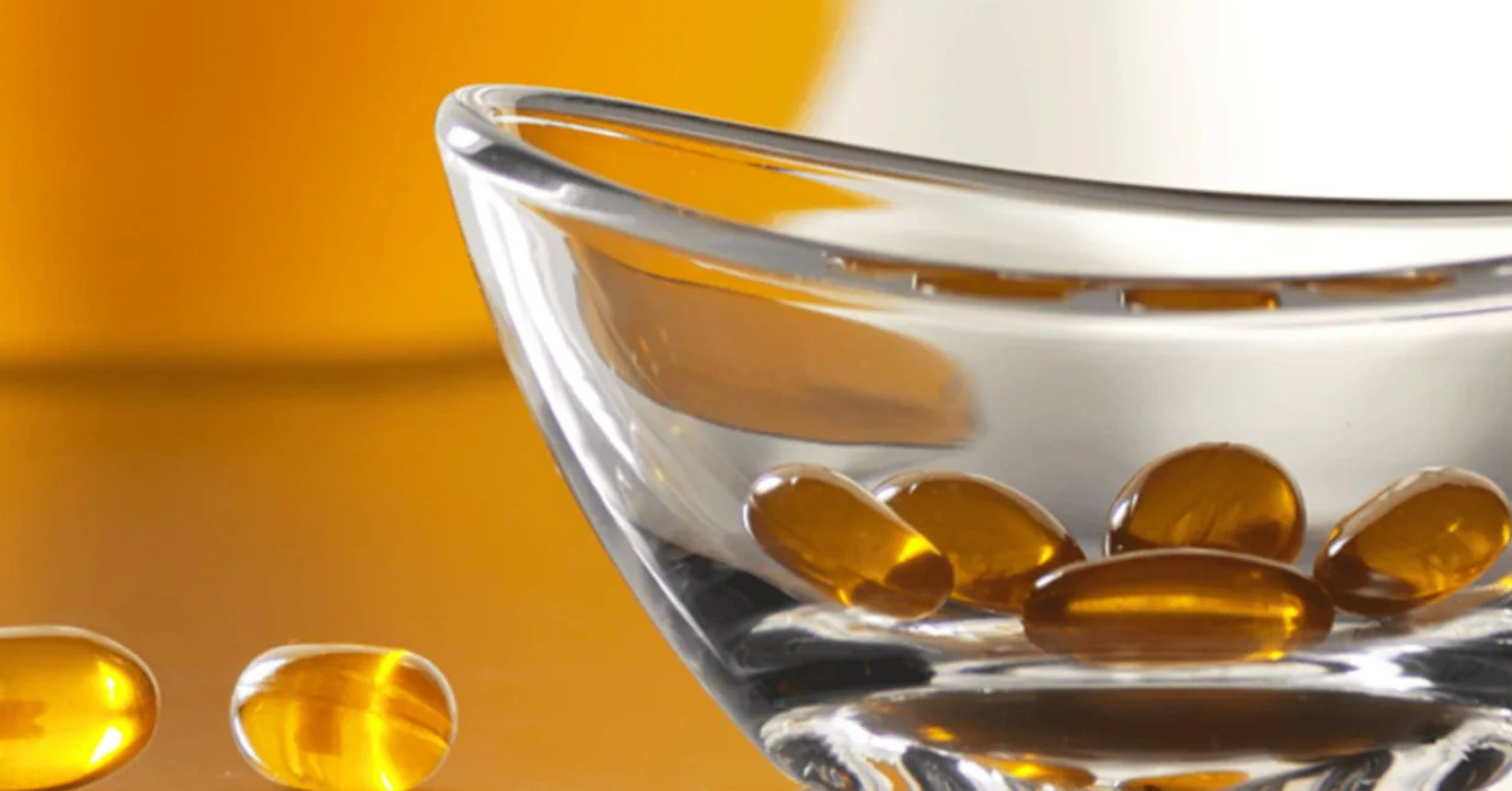 Yellow capsules in a glass bowl with a blurred yellow background