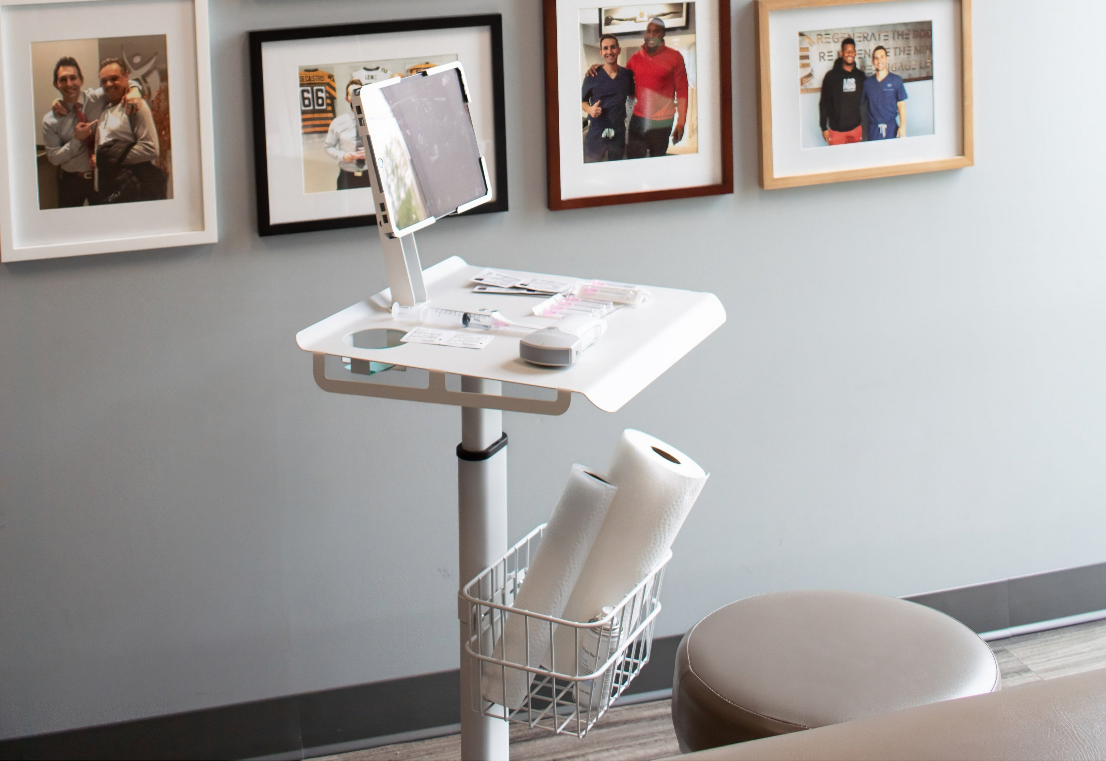 White adjustable desk with computer setup against a wall with framed photos