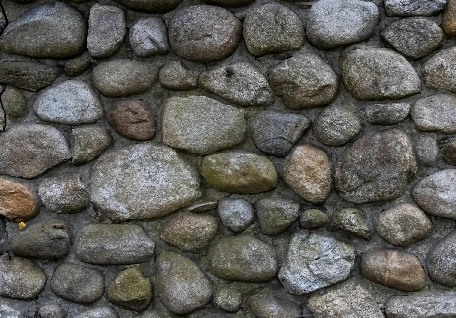 A close-up texture of a natural stone wall composed of irregular, smooth river rocks in shades of gray, brown, and beige.