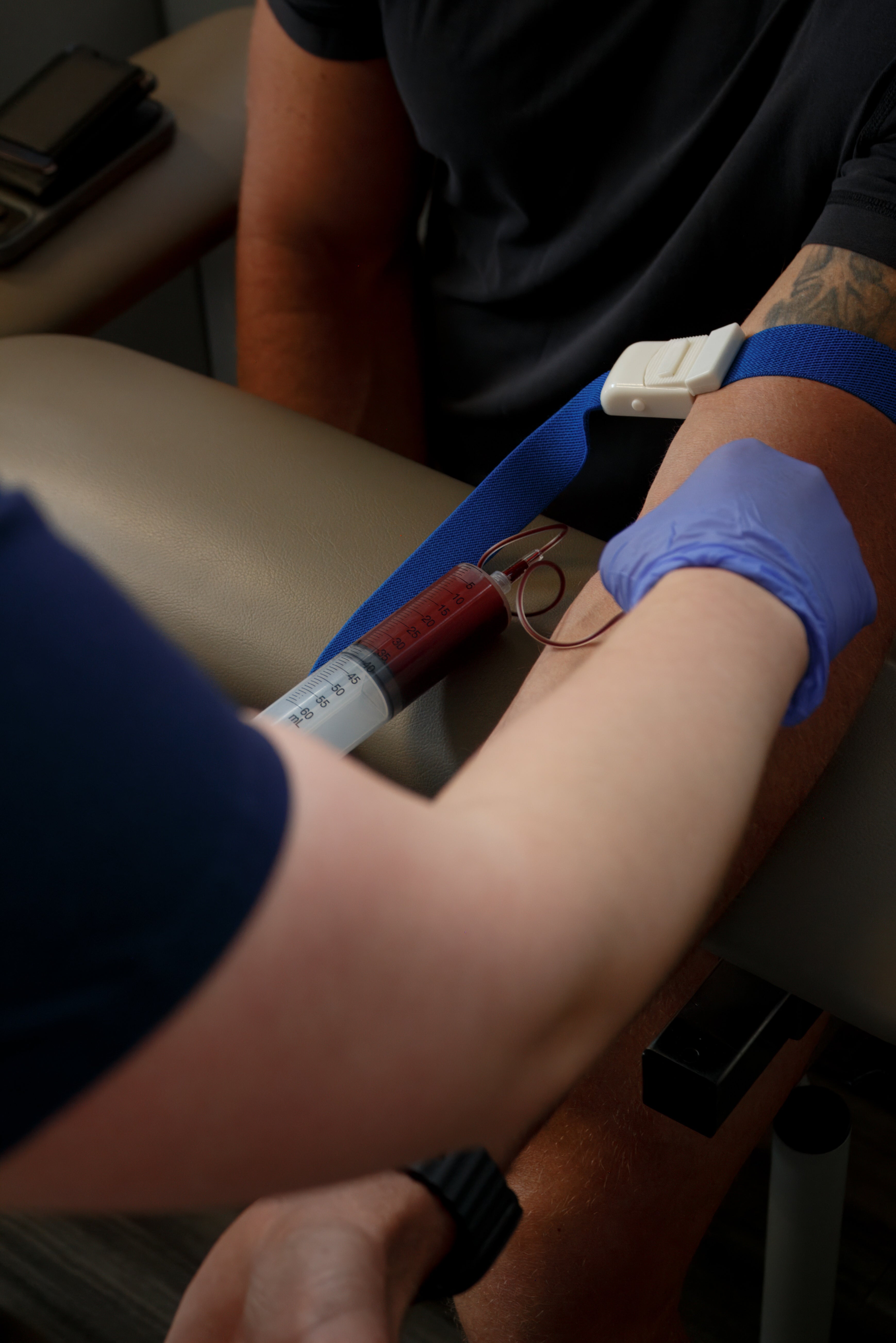Person receiving a blood draw with a medical professional wearing gloves.